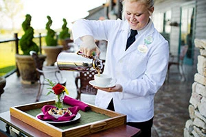 Student pouring coffee at patio table.